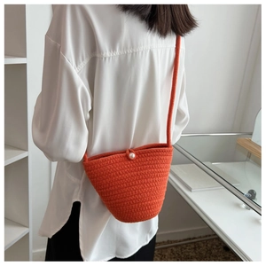 Detail of hand-woven orange bucket bag with a pearl buckle shown on model