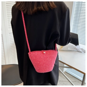 Detail of hand-woven magenta bucket bag with white pearl closure and spiral shoulder strap