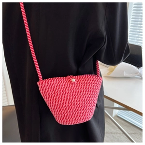 Detail of pink hand-woven bucket bag featuring a white pearl button and rope strap