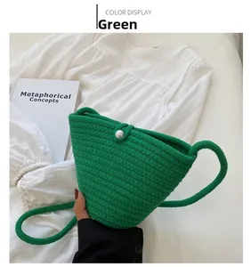 Close-up of green hand-woven bucket bag featuring knit texture and pearl button detail