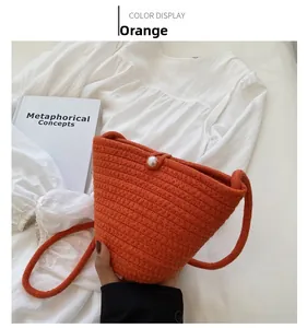 Detailed macro view of orange woven bucket bag with elegant pearl button accent