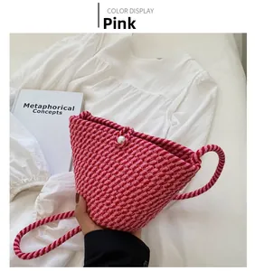 Detail view of a handmade pink woven bucket bag with pearl closure on white shirt