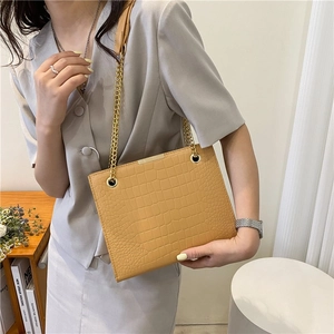 Chic ginger brown crocodile pattern tote bag with gold chain strap worn by a model