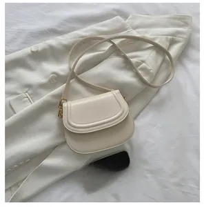 Detail view of cream saddle bag with gold buckle hardware and phone for size comparison