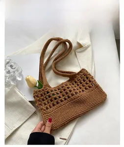 Dettaglio della borsa a tracolla in maglia marrone con motivo a rete su abito