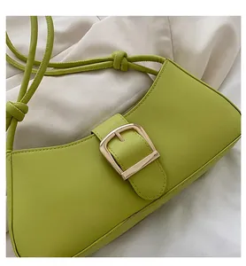 Detail of avocado green PU leather bag featuring a large gold square buckle and cord strap