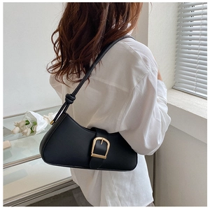 Close-up of black leather underarm bag with gold buckle and knot handle detail