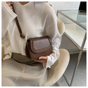 Brown vintage saddle bag detail showing smooth leather texture and gold hardware hooks