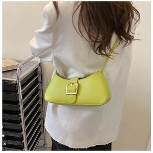 Fashionable fluorescent yellow baguette bag with oversized gold buckle on white blazer