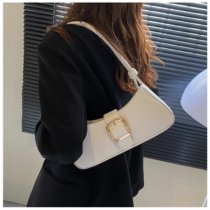 Detail of white leather underarm bag with gold buckle on a model wearing black blazer