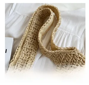 Detail of wide woven shoulder strap on beige straw tote bag with soft fabric lining
