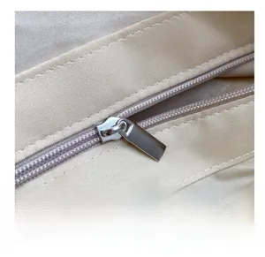 Close-up of smooth silver metal zipper on off-white woven straw tote shoulder bag