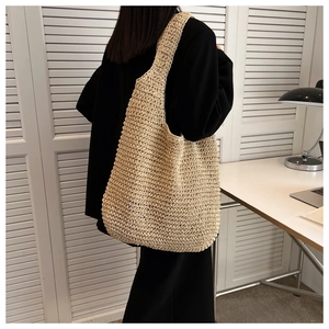 Close-up of beige woven hobo shoulder bag with textured rope patterns on model