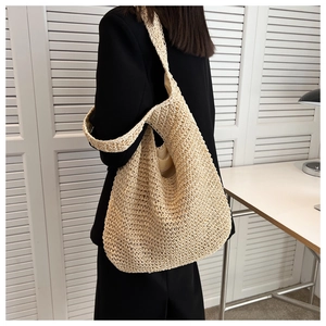 Chic cream woven straw tote bag shown on shoulder in a minimalist interior setting