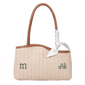 Woven straw shoulder bag with brown leather handles and a floral scarf accent