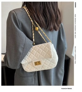 Close-up of white quilted crossbody bag with gold chain strap worn by a model