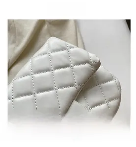 Close-up of white quilted leather texture and gold metal turn-lock on crossbody bag
