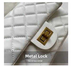 Close-up of golden metal twist lock and quilted texture on white crossbody bag