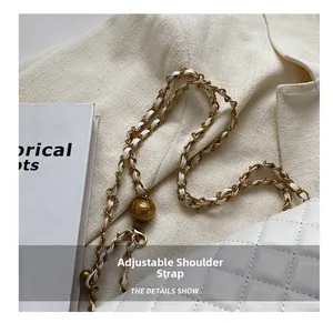 Close-up of white quilted leather chain bag featuring an adjustable gold bead buckle