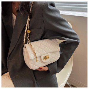 Close-up of white quilted chain bag with gold hardware worn with a grey suit blazer