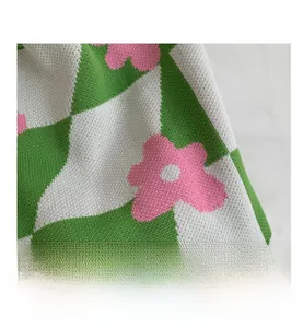 Macro shot of green and white checkerboard knit fabric with pink floral embroidery