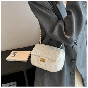 Detail of white quilted leather texture and gold metal clasp on a flap chain bag