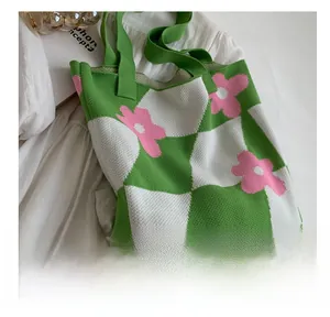 Close-up of green and white checkerboard knit tote bag with pink floral patterns