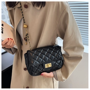 Close-up of black quilted shoulder bag with gold chain strap and turn-lock closure