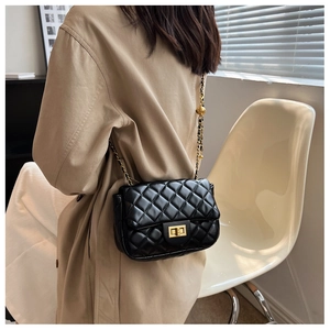 Classic black quilted crossbody bag with gold chain strap shown on a beige trench coat