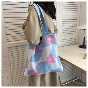 Close-up of knitted tote bag showing blue checkerboard pattern and pink floral accents