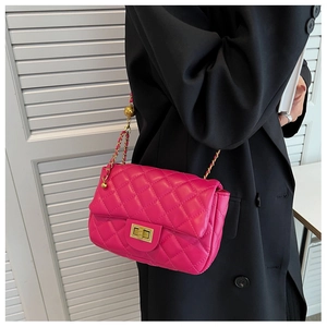 Detail view of fuchsia quilted crossbody bag with gold square lock and chain strap