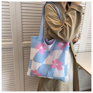 Detail view of a knitted tote bag featuring a blue checkerboard and pink floral pattern