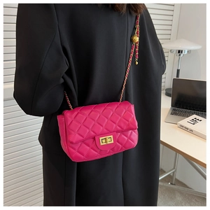 Detail of rose red quilted crossbody bag with gold chain strap and twist-lock clasp