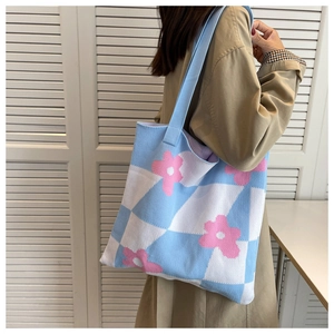 Close-up of knit tote bag featuring blue checkerboard pattern and pink floral details
