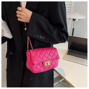 Chic magenta quilted crossbody bag with gold chain strap shown on a model