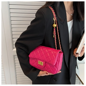 Detail of pink quilted flap bag with golden ball chain and metallic turn-lock closure