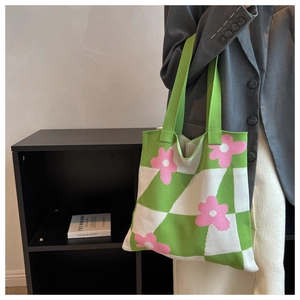 Detail of knit tote bag featuring green checkerboard pattern and pink flower design