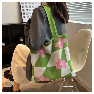 Detail of knitted tote bag with green checkered pattern and pink flower accents