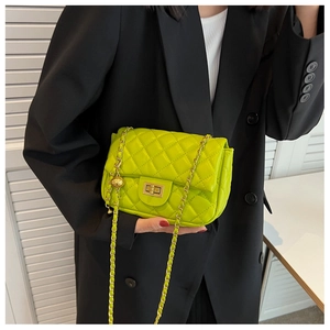 Close-up of lime green quilted handbag with gold square clasp and woven chain strap
