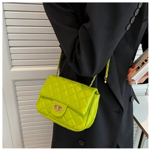Detail of neon green quilted crossbody bag with gold twist lock on black blazer