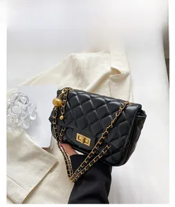 Close-up of quilted black leather bag with gold clasp and metallic ball chain detail