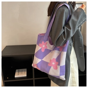 Detail of knitted tote bag with purple checkerboard pattern and floral embroidery accents