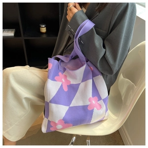 Detailed knit of purple checkered tote bag with pink flowers held by a model