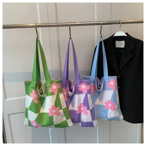 Detail of floral checkered knitted tote bags in green, purple and blue displayed on hangers