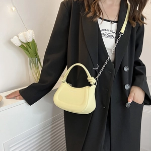 Light yellow minimalist saddle bag with knotted handle and chain strap on a model