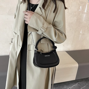 Minimalist black crossbody handbag with knotted handle and silver chain on model