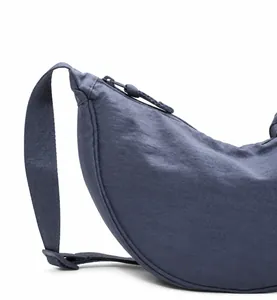 Detalle del bolso de media luna azul oscuro con textura de nailon y cremallera