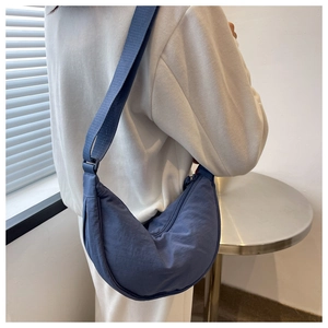 Dark blue nylon crescent crossbody bag shown on model in a modern interior setting