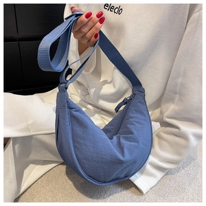 Detailed view of the blue nylon crescent crossbody bag worn with an adjustable strap