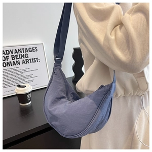 Blue crescent nylon crossbody bag on model with natural pleated fabric texture detail